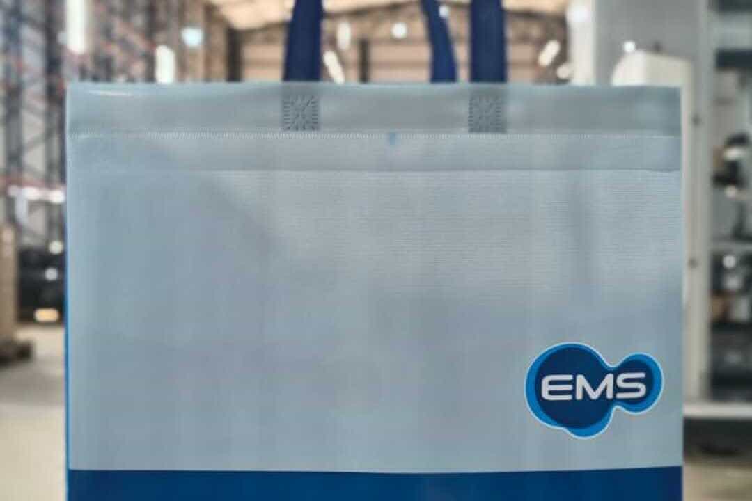 Sacola branca e azul de TNT com logo da empresa, exemplo de sacolas personalizadas grandes marcas usadas em ações corporativas sustentáveis.