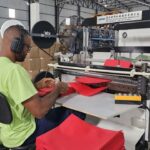 Profissional operando máquina industrial durante o processo de fabricação de sacolas sustentáveis para empresas, em ambiente fabril organizado e tecnológico.
