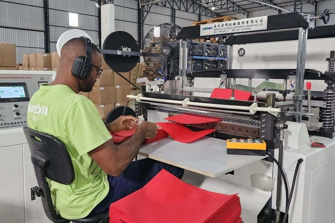 Profissional operando máquina industrial durante o processo de fabricação de sacolas sustentáveis para empresas, em ambiente fabril organizado e tecnológico.
