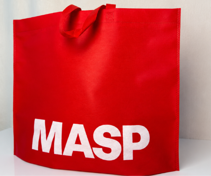 Sacola vermelha personalizada com a marca MASP em destaque, posicionada sobre uma superfície clara.