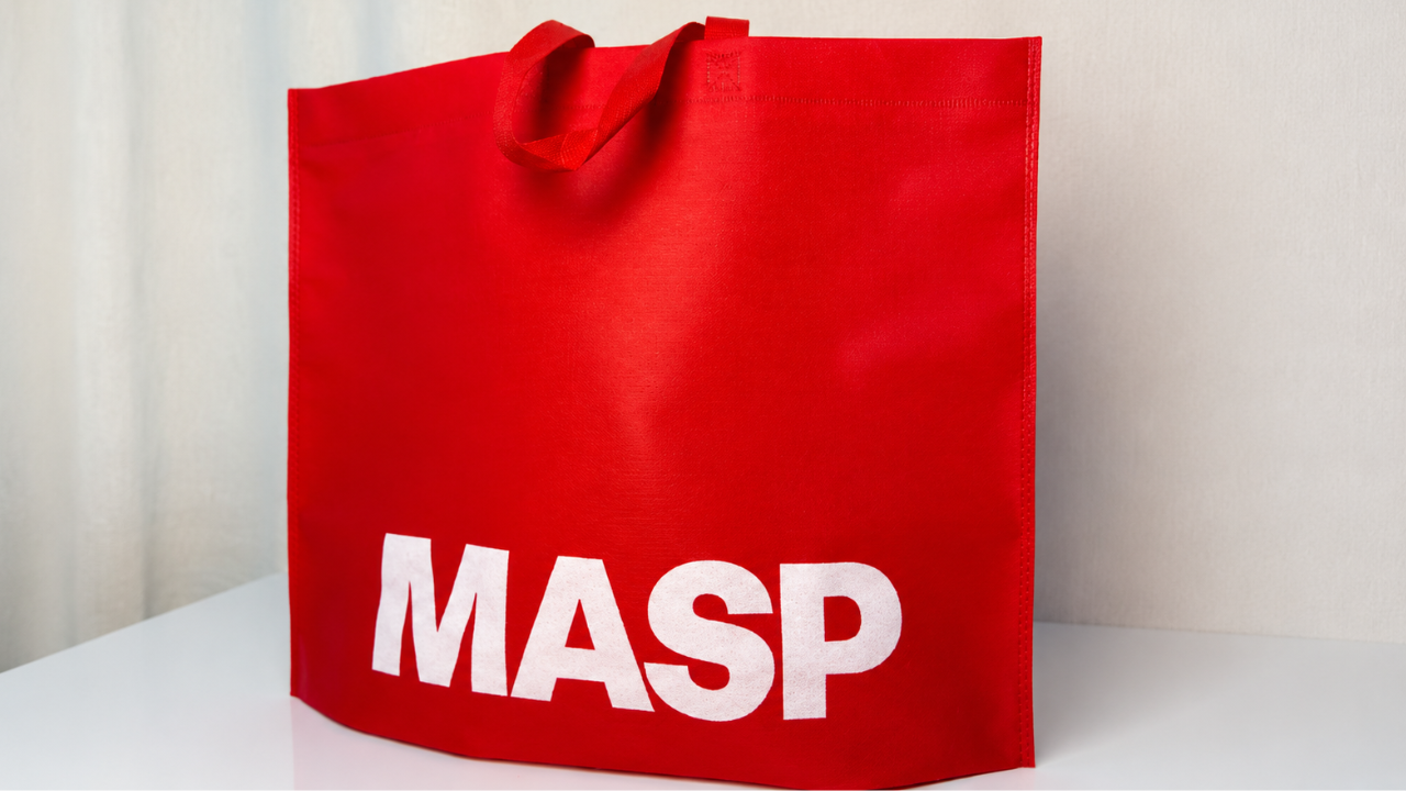 Sacola vermelha personalizada com a marca MASP em destaque, posicionada sobre uma superfície clara.