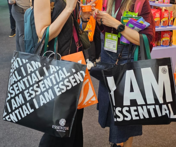 Pessoas em evento corporativo carregando sacolas personalizadas da Essential Nutrition.