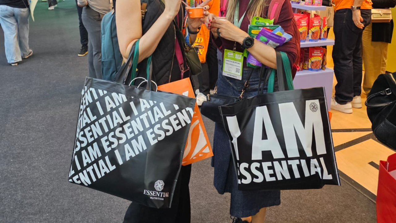 Pessoas em evento corporativo carregando sacolas personalizadas da Essential Nutrition.